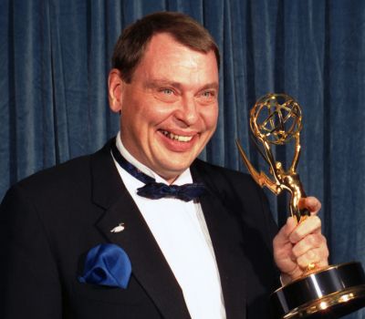 Late Actor Larry Drake holding posing for a photo shoot while holding an award.